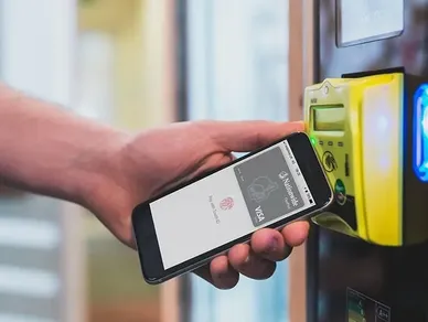 A person holding their phone in front of a yellow machine.