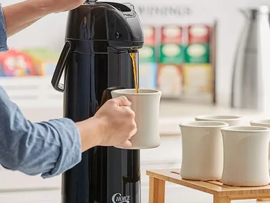 A person pouring liquid into a cup from a coffee pot.