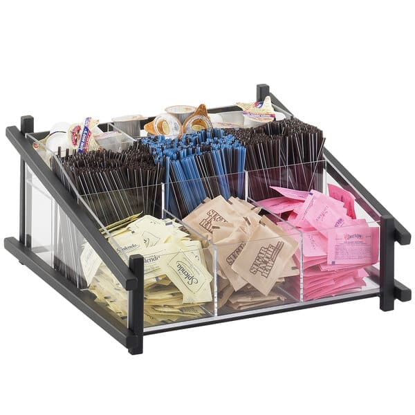 A Cal-Mil One by One Black Condiment Organizer filled with various packets of sugar, sweeteners, and stirrers on a countertop.