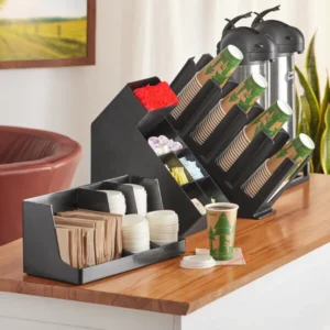 A Choice Black Plastic Countertop Coffee Organizer Station Set stocked with disposable cups, lids, stirrers, and condiments on a wooden table.