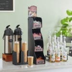 Coffee station with dispensers and cups.