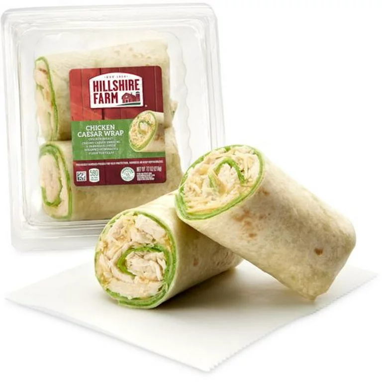 Packaged Hillshire Farm Chicken Caesar Wrap in a plastic container, with one wrap cut in half to show the filling.