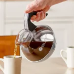 Hand pouring coffee from a Bunn carafe.