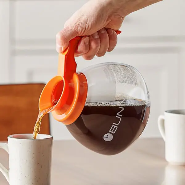 Hand pouring coffee from a carafe.