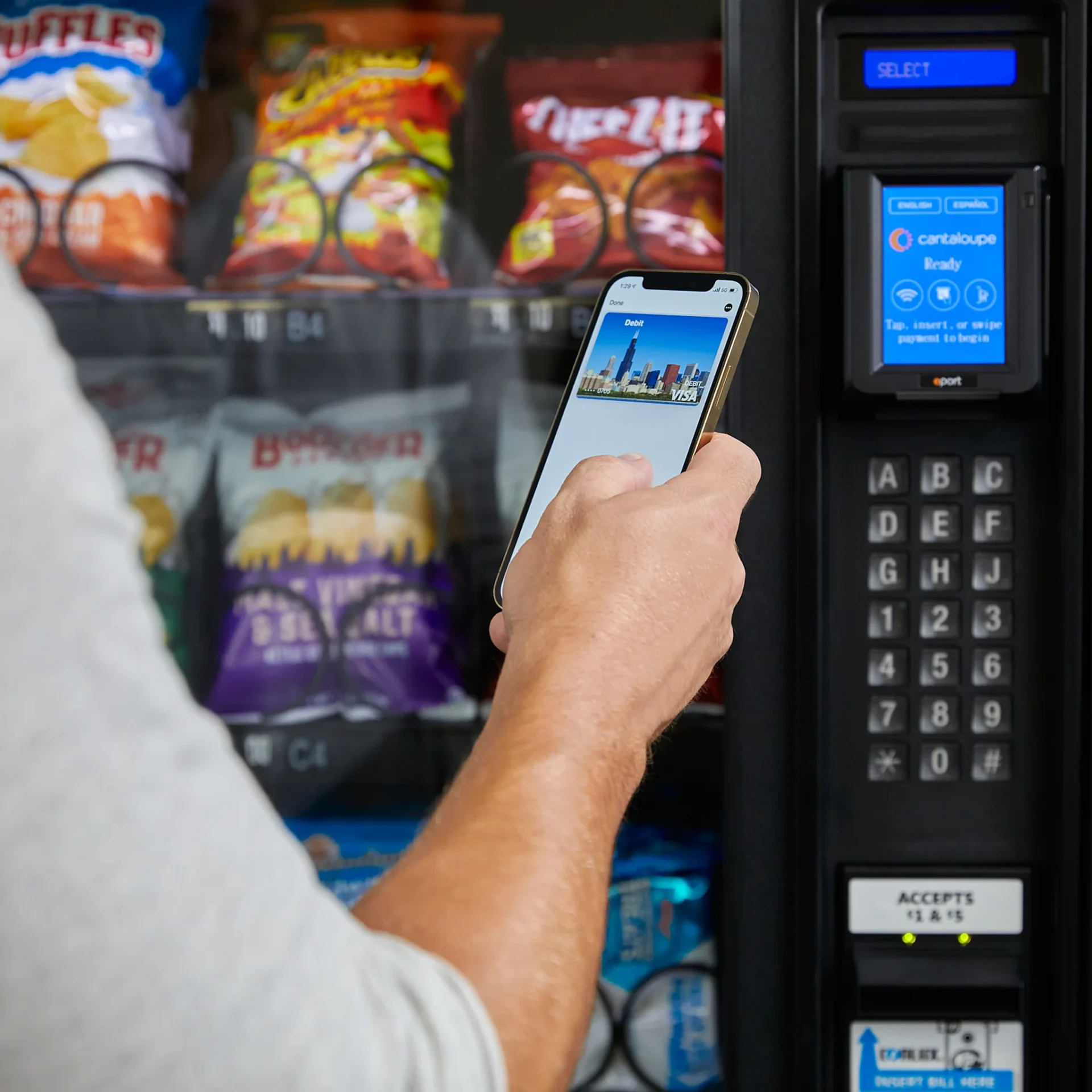 Person using phone to pay at vending machine.